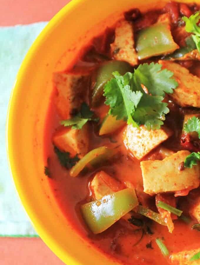 Kadhai Paneer on a yellow bowl with lots of veggies and garnished with coriander leaves