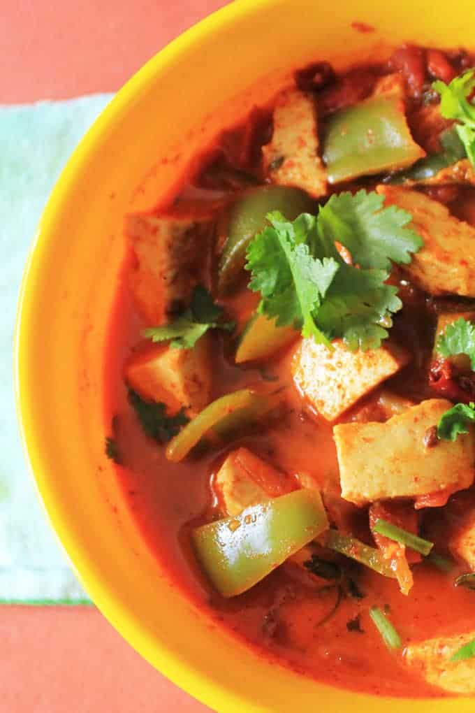 Kadai Paneer served on a yellow bowl with lots of veggies and garnished with coriander leaves 