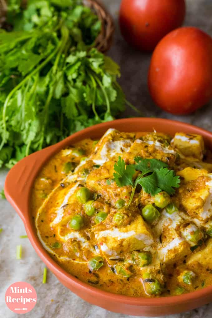 Matar Paneer on a transparent plate on a white surface 