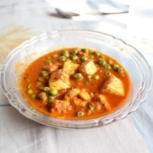 Matar Paneer on a transparent plate on a white surface