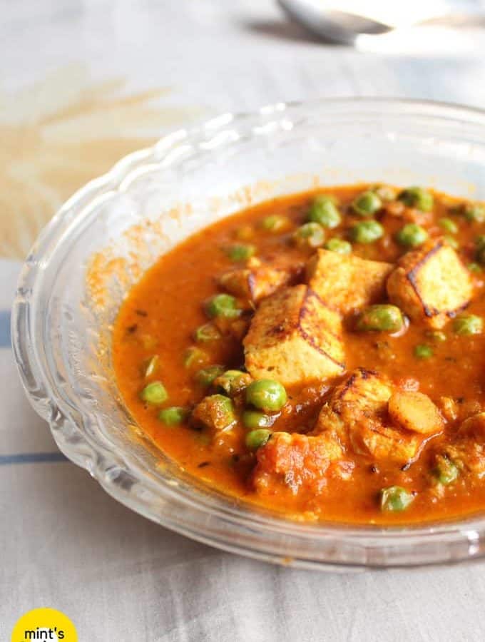 Matar Paneer on a transparent plate on a white surface