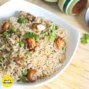 Matar paneer pulao in a white bowl with some coriander leaves kept on a wooden surface with top wooden bowlsin the background |