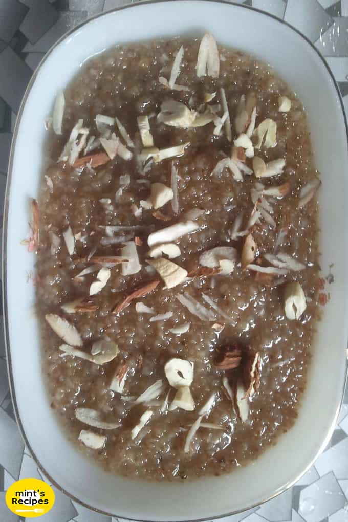 Meetha daliya on a white plate with lots of chopped cashew and almonds in it 