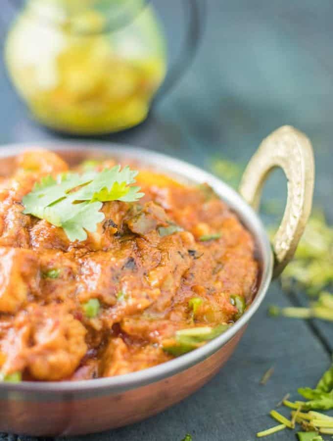Mixed vegetables on a deep vessel with some coriander leaves. keeped on a dark surface with some chopped coriander leaves|