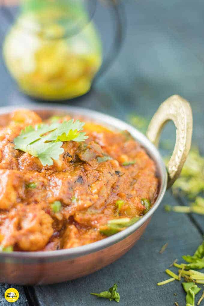 Mixed vegetables on a deep vessel with some coriander leaves. keeped on a dark surface with some chopped coriander leaves|