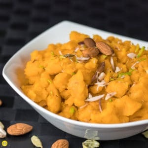 Moongdal ka halwa on a yellow bowl garnished with almonds
