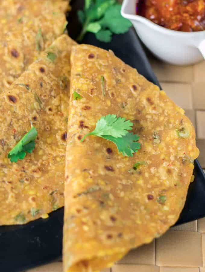 Sabut moongdal ka paratha on a black tray with some coriander leaves