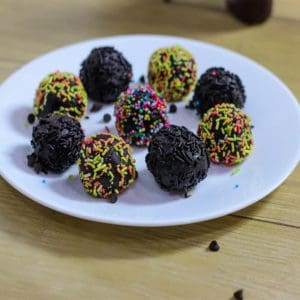 Chocolate Biscuit Balls on a white plate with some biscuit balls coated with colorful sprinklers