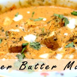 Paneer butter masala on a floural printed plate garnished with some fresh cream and coriander leaves |