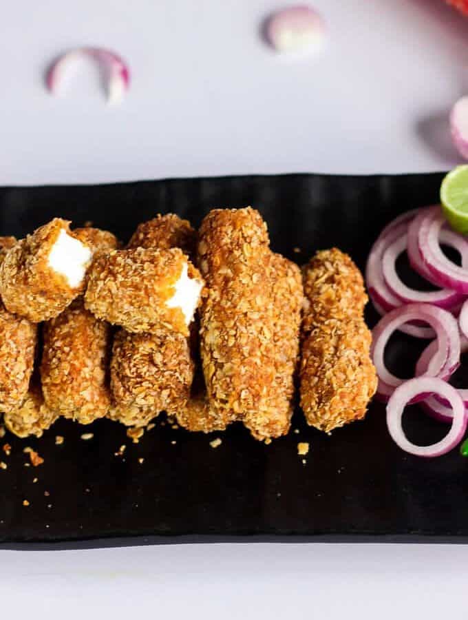 Paneer Finger on a black plate with some onion rings
