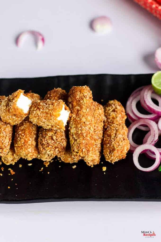 Paneer Finger on a black plate with some onion rings