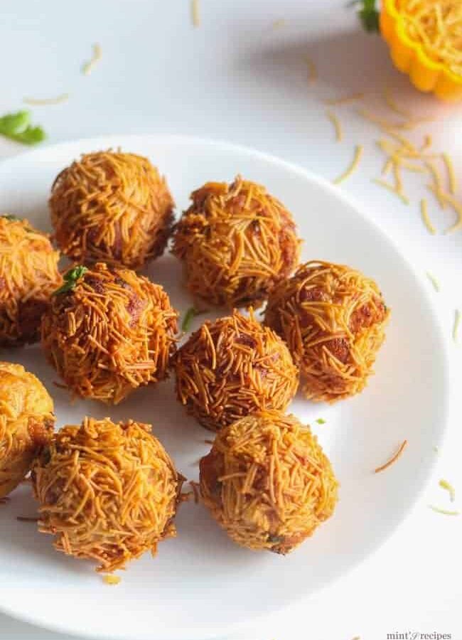 Paneer Vermicelli Balls on a white plate with some sev sprinklers garnished with some coriander leaves