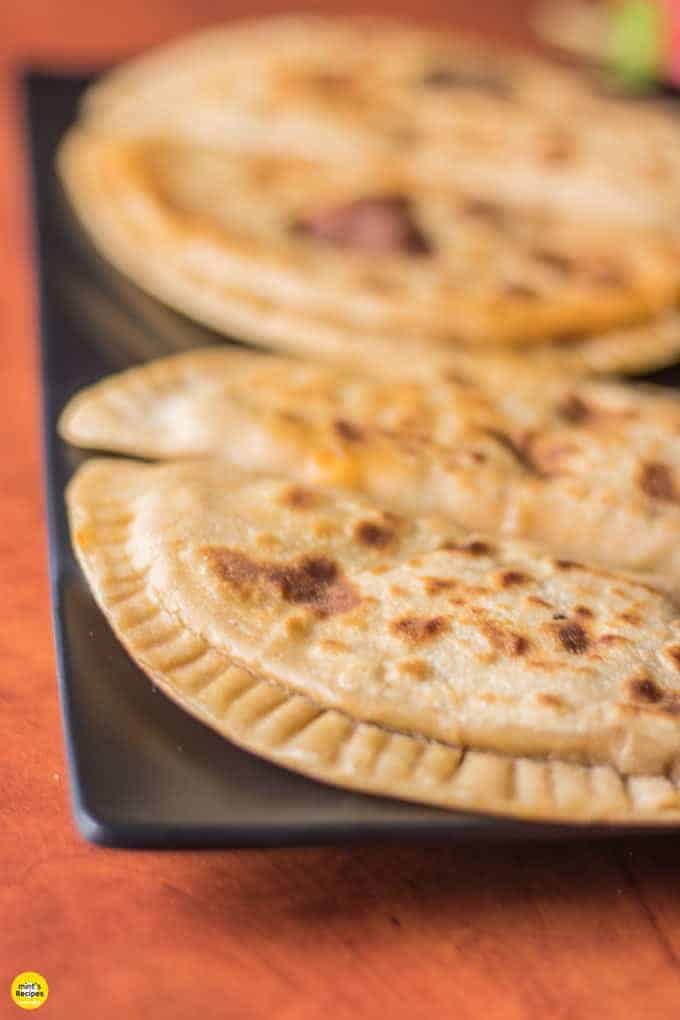 Pizza paratha on a black plate with a blur effects on a brown board surface