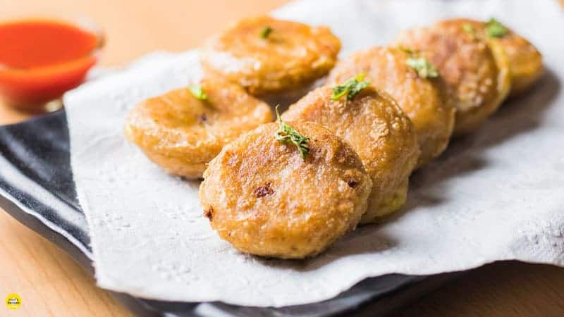 Potato Cheese Corn Rolls| Potato cheese corn rolls on a white plate with an absorbing paper and some coriander leaves to garnish |