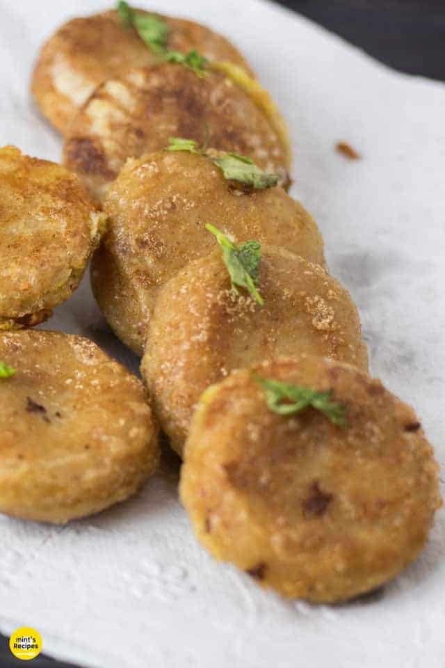 Potato Cheese Corn Rolls| Potato cheese corn rolls on a white plate with an absorbing paper and some coriander leaves to garnish |