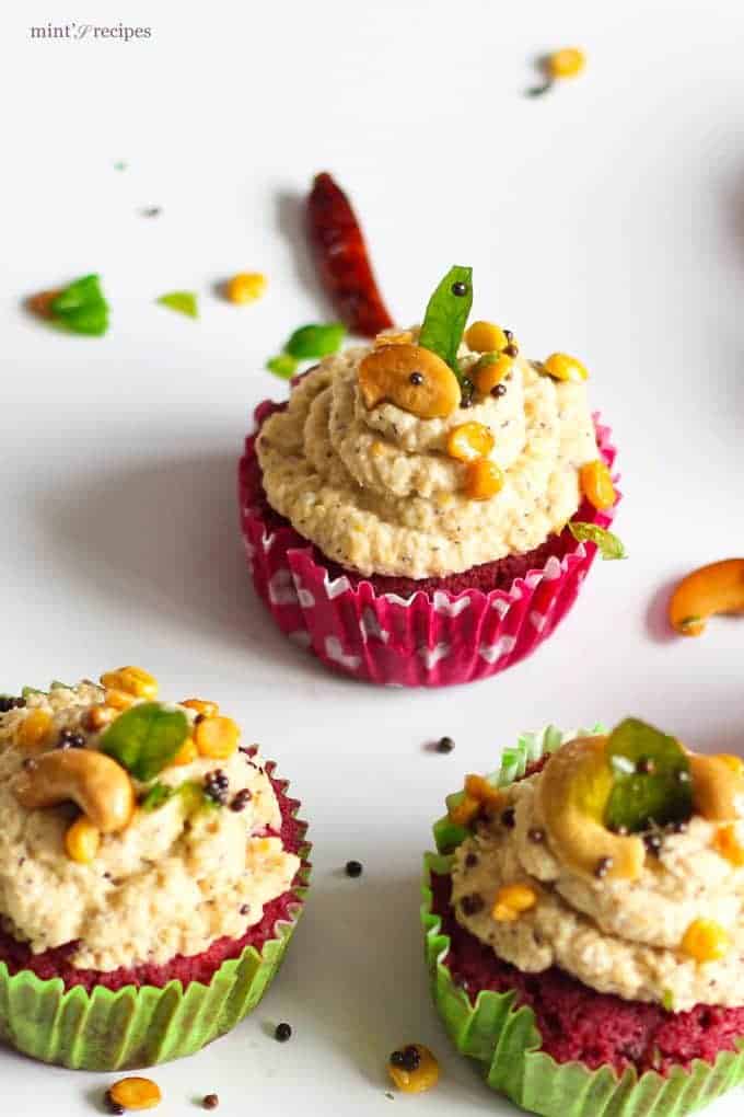 Red Velvet Idli Cupcake on a white surface with tempering of coconut chutney and little temmpering of curry leaves, mustard seed, chana dal and cashew |
