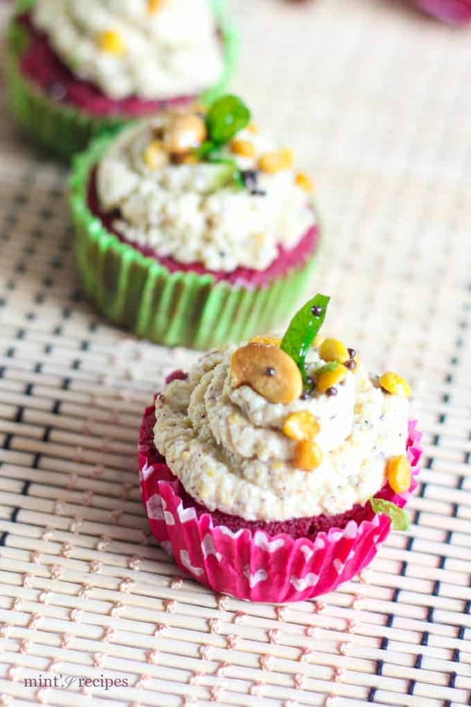 Red Velvet Idli Cupcake on a white surface with tempering of coconut chutney and little tempering of curry leaves, mustard seed, chana dal and cashew |
