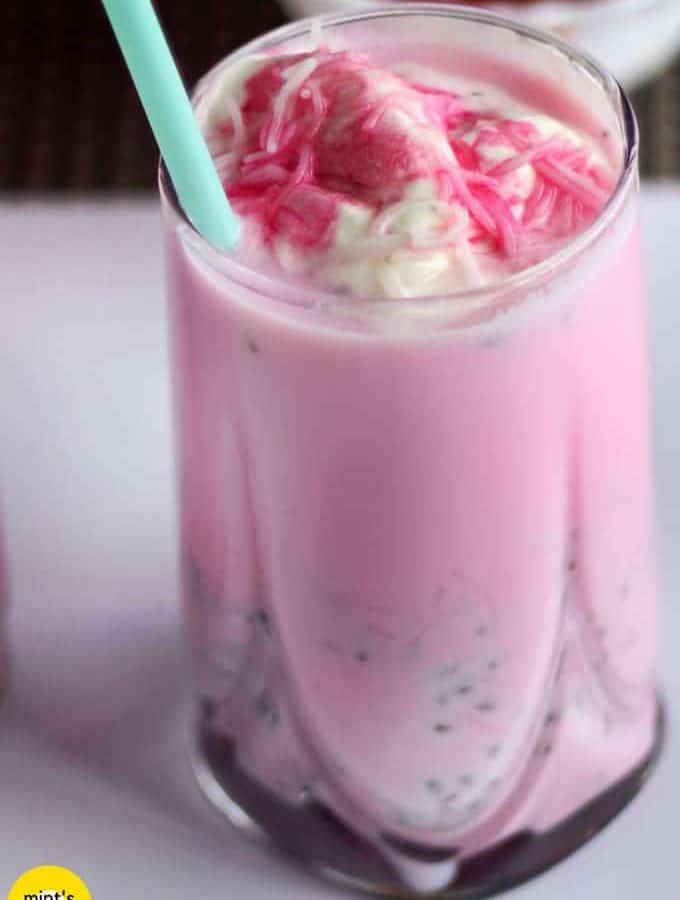 Rose Milkshake on a glass filled with rose milkshake and vanilla icecream with varmicelli and a strow in it|