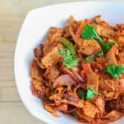 Roti noodles on a white bowl full with roti noodles and garnished with coriander leaves with a light background