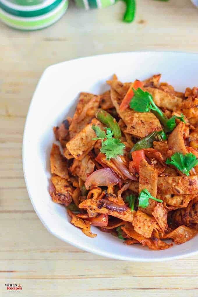 Roti noodles on a white bowl full with roti noodles and garnished with coriander leaves with a light background