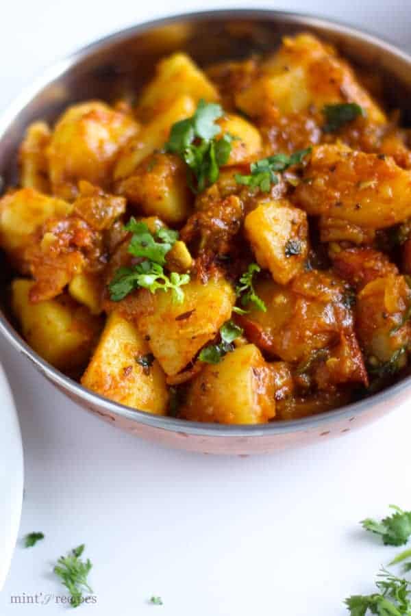 Spicy Potato Curry on a deep vessels garnished with some coriander leaves
