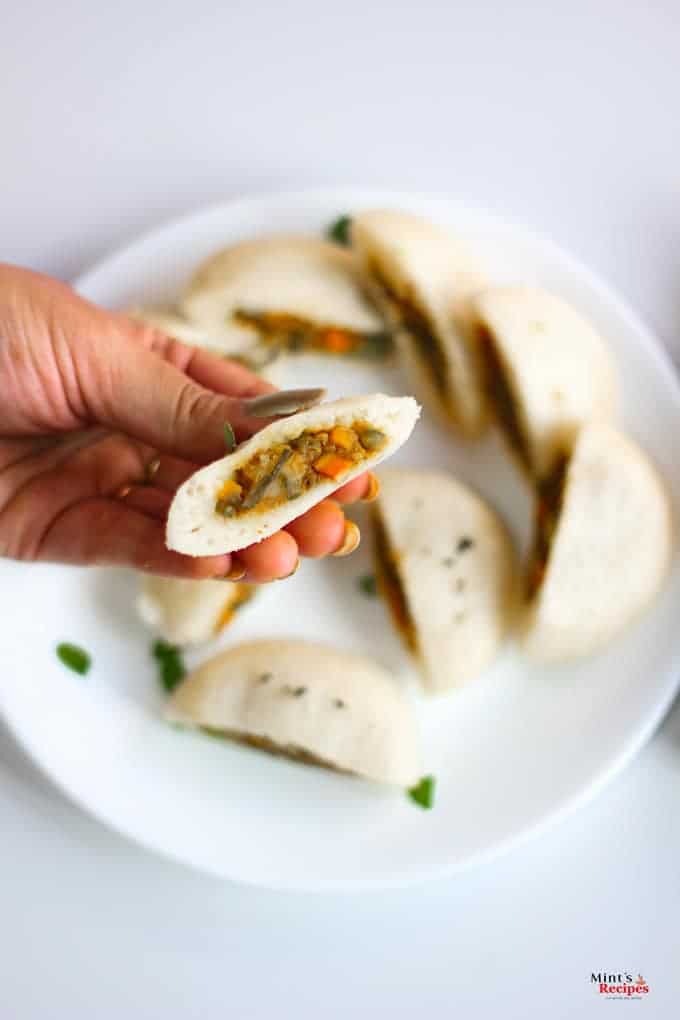 Stufffed Rava Idli on a white plate with some curry leaves and some coconut chutney