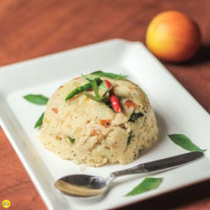 Suji upma on a white plate garnished with some curry leaves and green chili with some bell peppers in the background