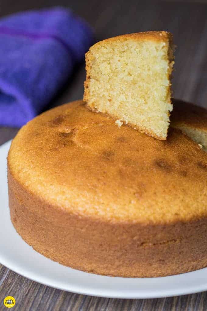 Eggless Vanilla Cake in a black plate with some gems on a white surface |