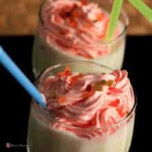 Vanilla milkshake on glass with some tutti fruity sprinkles on it with a strow on a dark background |