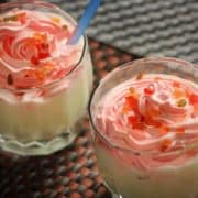 Vanilla milkshake on glass with some tutti fruity sprinkles on it with a strow on a dark background |