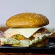 Vegetable Burgers on a black rectangular tray with some onion slices kept on a dark paper surface with dark background |