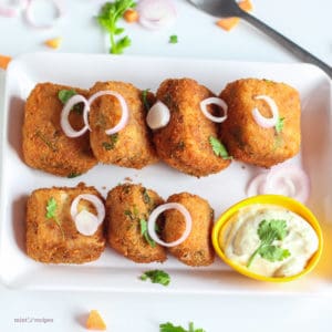 Veg Paneer Cheese Bites With Mayo Dip on a white plate with some onion rings