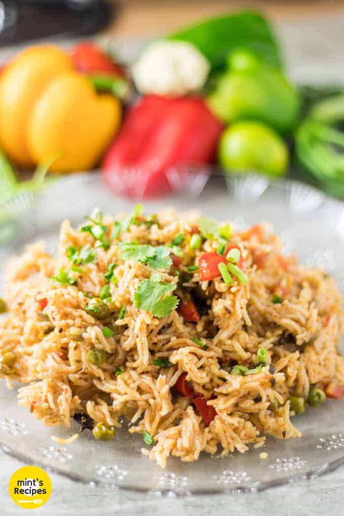 Vegetable Pulao on a tranparent plate garnished with some coriander 