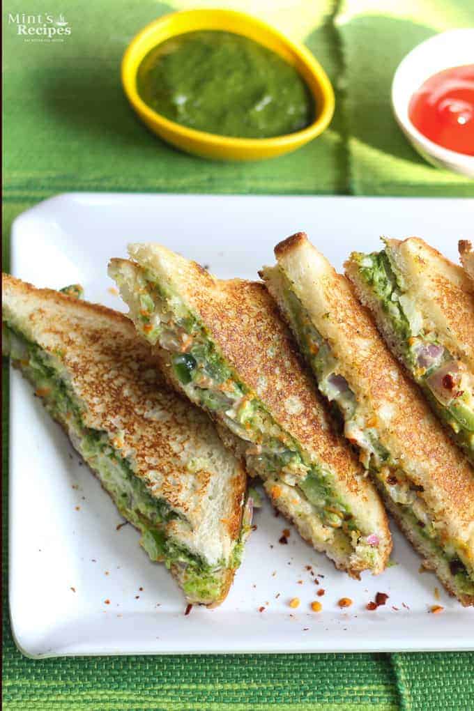 Veg Mayonnaise Sandwich Recipe on a white tray with chilli flakes and some green chutney and tomato ketchup on the background |