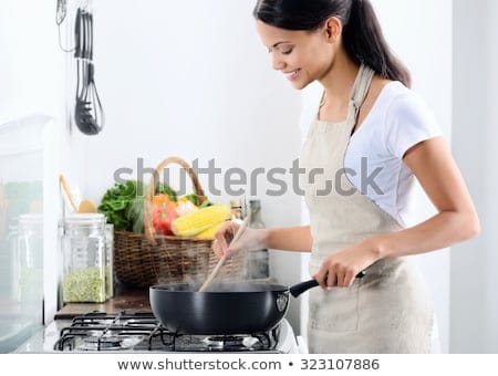 woman standing by stove kitchen 450w 323107886
